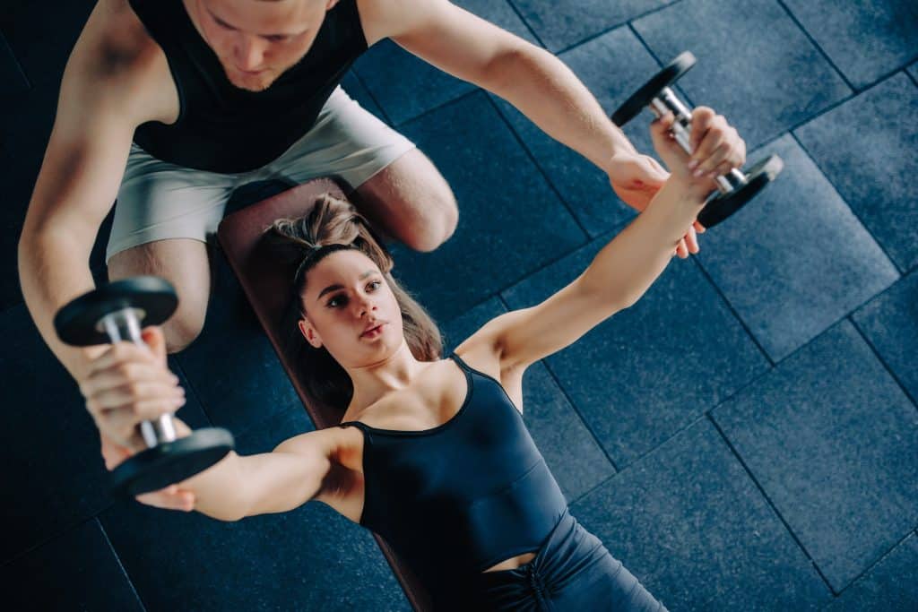 A trainer spotting an athlete doing chest flies