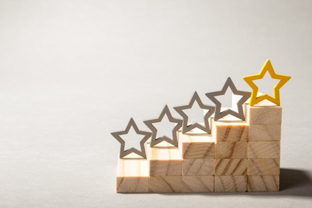 A wooden block with five steps, and a star shape on each, representing a five-star review