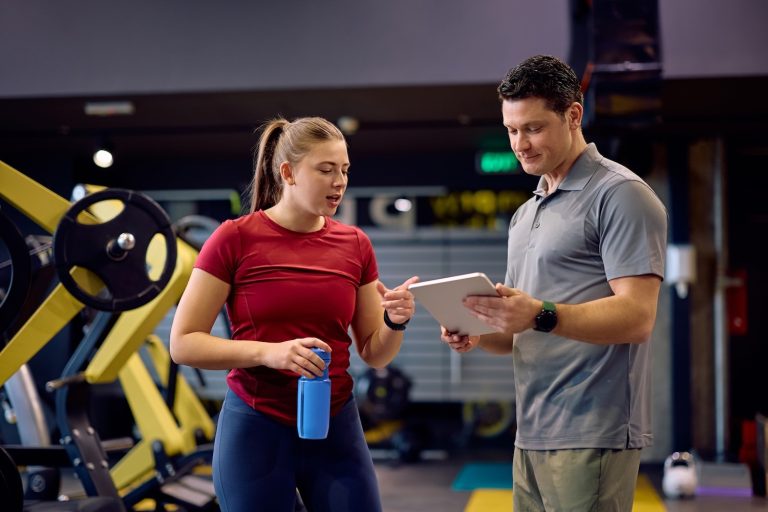 A personal trainer showing a client their digital tablet inside a gym