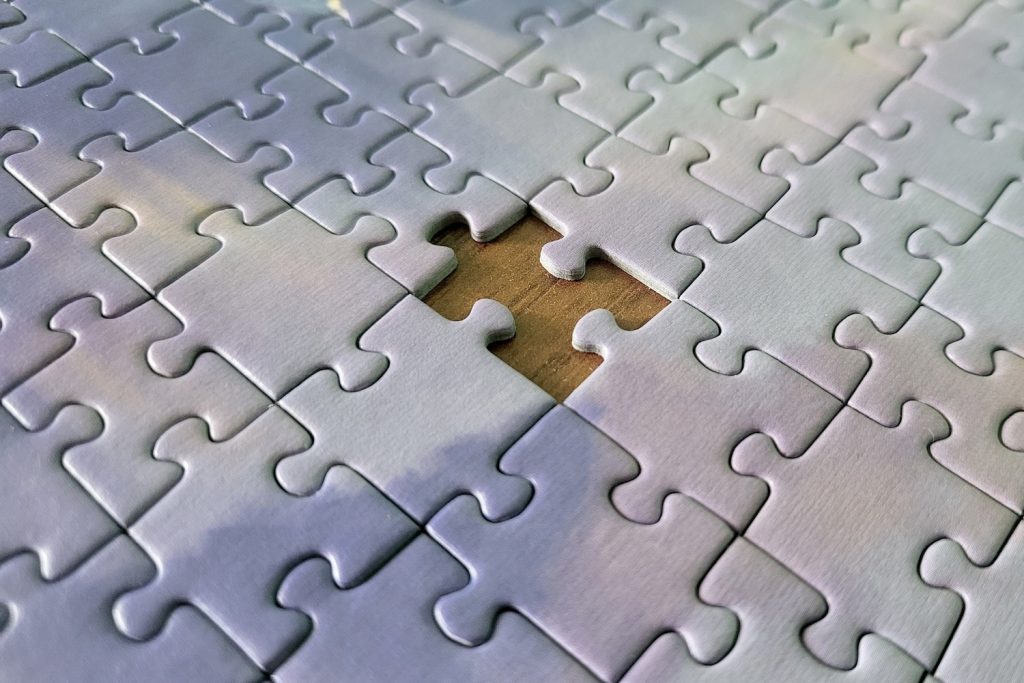 A puzzle with of white pieces with one piece missing at the center