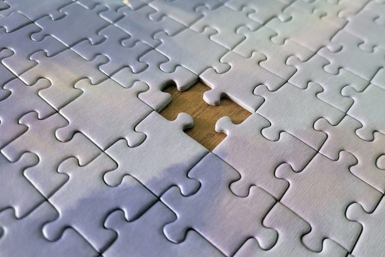 A puzzle with of white pieces with one piece missing at the center