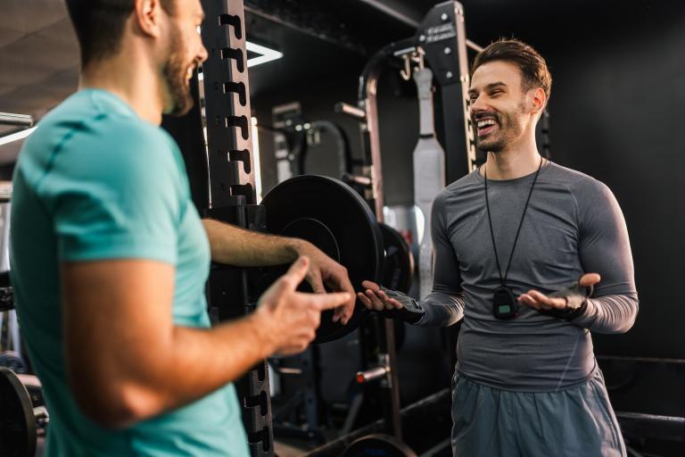 Athletic man talking with a personal trainer in the gym